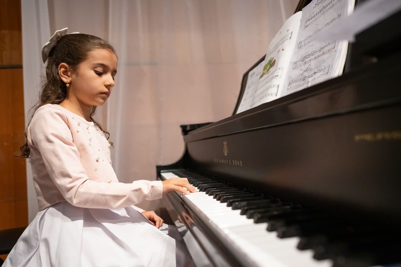 Aluna do Piano Kids tocando ao piano de cauda em recital do Studio88