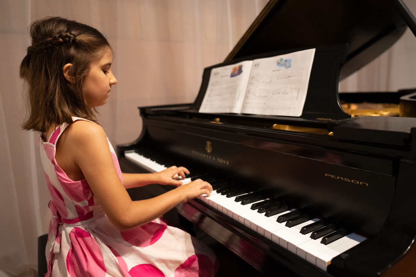 Aluna do Piano Kids tocando ao piano de cauda em recital do Studio88