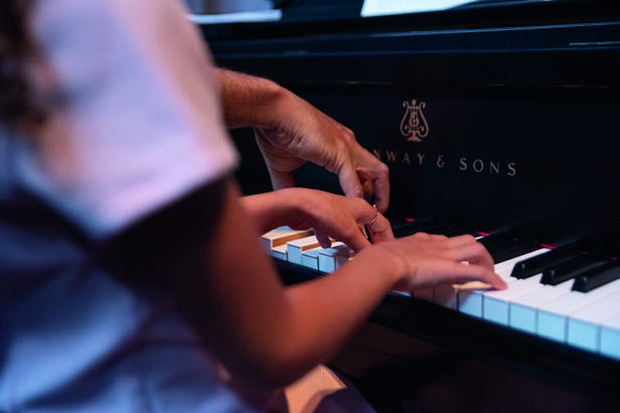 Professor do Studio88 orientando aluna ao piano de cauda