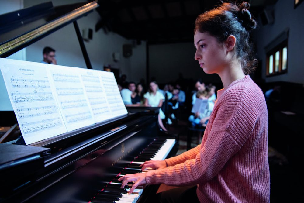 Aluna do Studio88 tocando piano de cauda em recital